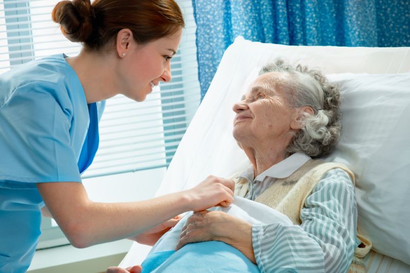 Nurse cares for elderly woman lying in bed