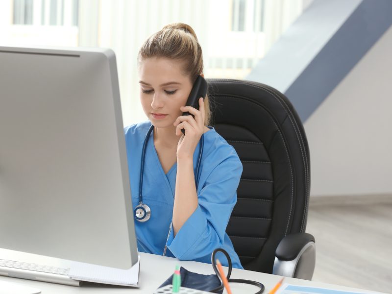 Young medical assistant talking by telephone while working in office