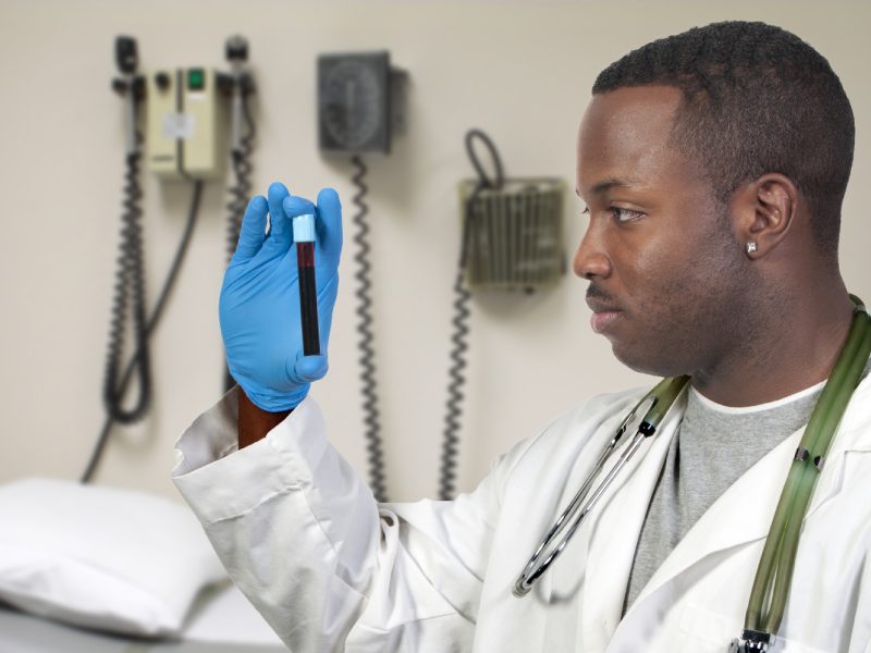 A black man African American doctor holding a test tube vial sample of blood