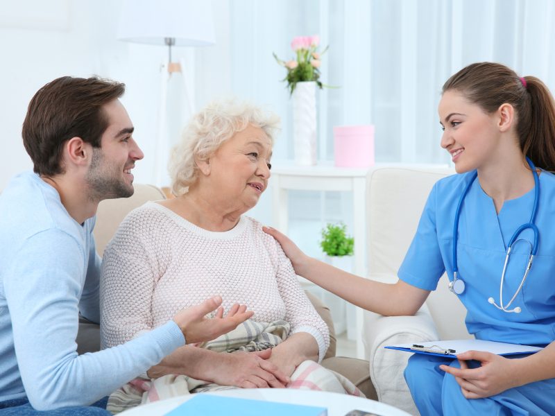 Nurse talking with grandmother and her grandson indoors
