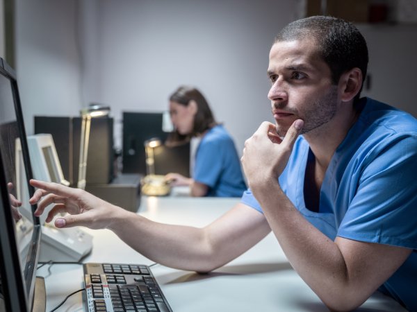 Male and Female lab technicians looking at scan after MRI in hospital laboratory. Young caucasian doctors or medical students working with computer for medical exam in clinic. People and professional