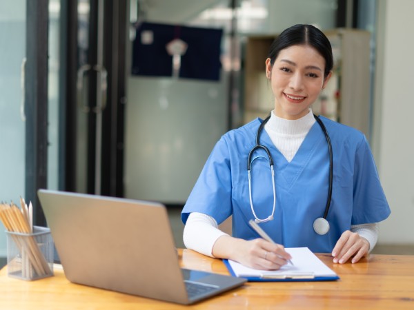Mujer médico con ordenador portátil trabajando en la mesa de la oficina.